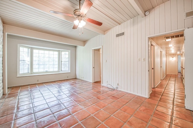 empty room featuring light tile patterned flooring, a ceiling fan, beamed ceiling, and wood ceiling