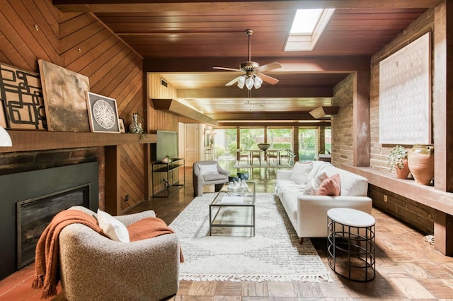 living room featuring wood ceiling, wooden walls, a glass covered fireplace, and a ceiling fan