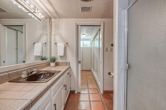 bathroom with vanity, an enclosed shower, tile patterned flooring, and baseboards