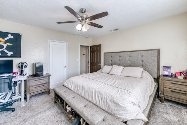 bedroom featuring light colored carpet, ceiling fan, and an office area