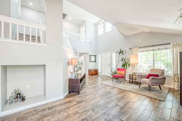 sitting room featuring wood finished floors, baseboards, and high vaulted ceiling