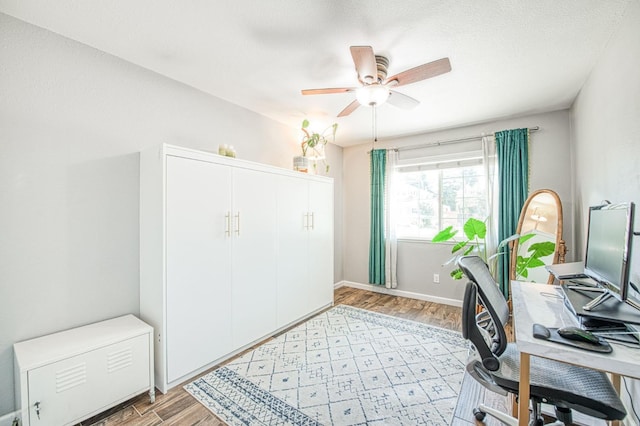 office area with light wood-style flooring, ceiling fan, and baseboards