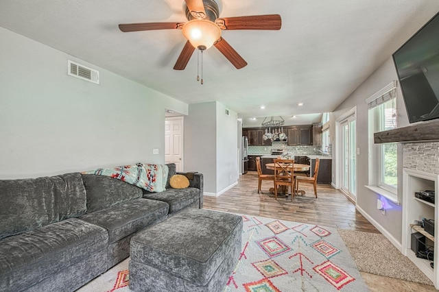 living area featuring light wood-style flooring, baseboards, a ceiling fan, and recessed lighting