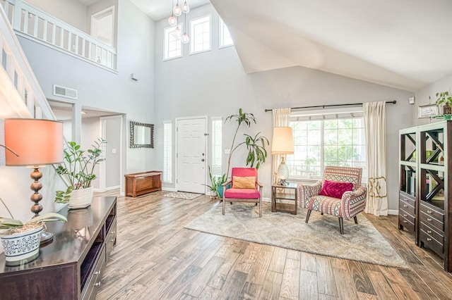 sitting room with wood finished floors, baseboards, and high vaulted ceiling