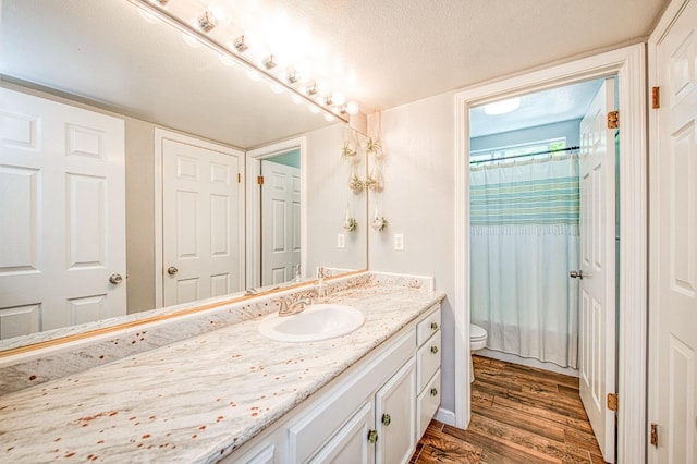 full bath with toilet, wood finished floors, vanity, a shower with shower curtain, and a textured ceiling