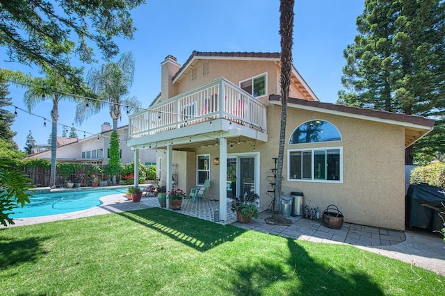 rear view of property with stucco siding, a patio, a balcony, and a chimney