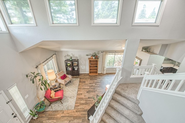 stairs featuring wood finished floors, a towering ceiling, and baseboards