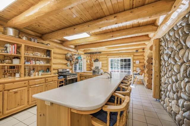 55585 Flintridge Dr, Shaver Lake, CA 93664 - kitchen with stainless steel range with gas cooktop, light tile patterned flooring, light countertops, beamed ceiling, and log walls