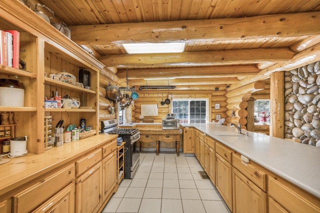 55585 Flintridge Dr, Shaver Lake, CA 93664 - kitchen featuring stainless steel gas stove, rustic walls, a sink, beamed ceiling, and light tile patterned floors