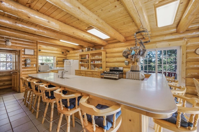 55585 Flintridge Dr, Shaver Lake, CA 93664 - kitchen with gas stove, freestanding refrigerator, beamed ceiling, log walls, and wooden ceiling