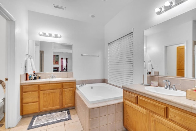 full bathroom with tile patterned flooring, a bath, two vanities, and toilet