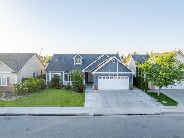 traditional home featuring an attached garage, a front yard, driveway, and stone siding