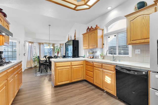 kitchen featuring dishwasher, lofted ceiling, light wood-type flooring, a sink, and a peninsula