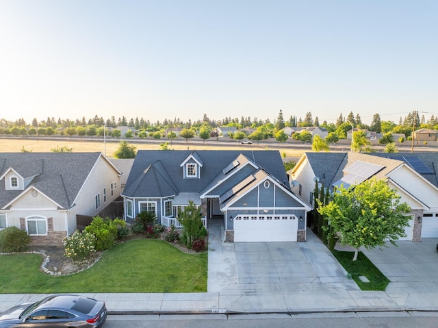 view of front of home with an attached garage, a front yard, concrete driveway, stone siding, and a residential view