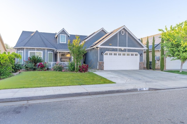 view of front of house with an attached garage, a front lawn, driveway, covered porch, and stone siding