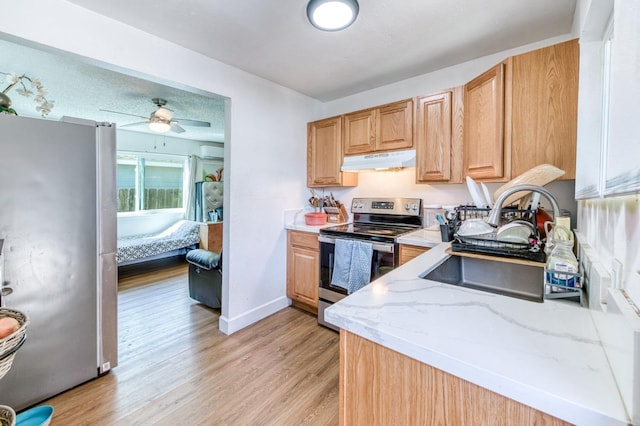 kitchen featuring stainless steel appliances, under cabinet range hood, light wood-style floors, ceiling fan, and baseboards