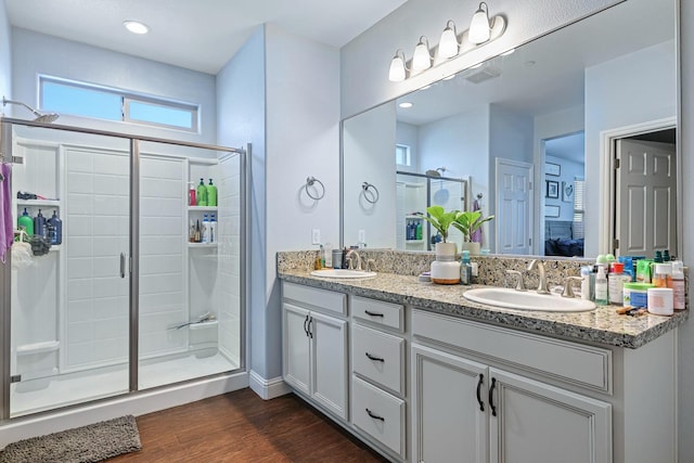 bathroom with a shower stall, wood finished floors, double vanity, and ensuite bathroom