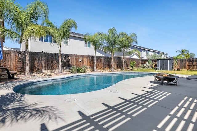 view of swimming pool with an outdoor fire pit, a patio area, a fenced backyard, and a shed