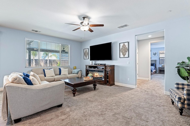 living area featuring ceiling fan, baseboards, carpet, and a fireplace