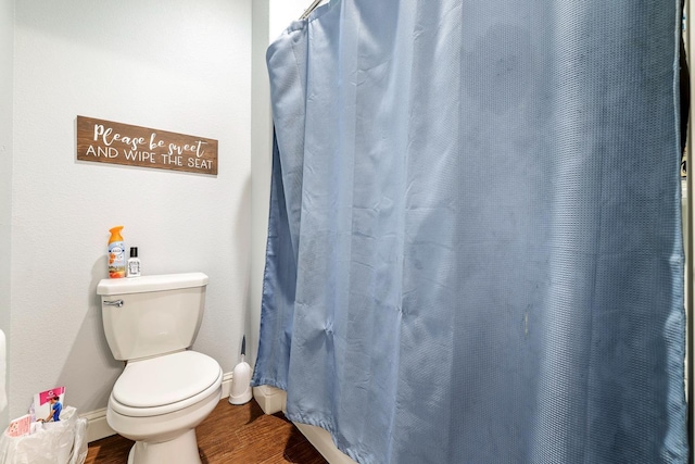 bathroom featuring wood finished floors, toilet, baseboards, and a shower with shower curtain