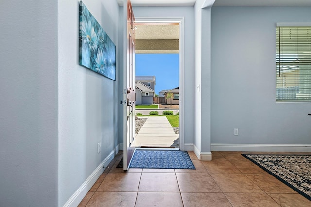 entryway featuring baseboards, tile patterned flooring, and plenty of natural light