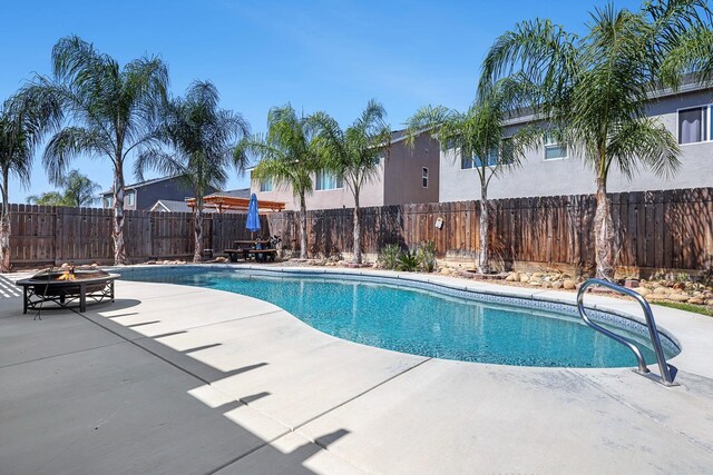 view of swimming pool featuring an outdoor fire pit, a patio, and a fenced backyard