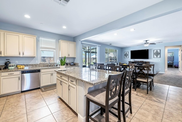 kitchen featuring stainless steel dishwasher, a sink, a breakfast bar area, healthy amount of natural light, and recessed lighting