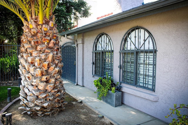 entrance to property featuring stucco siding and fence