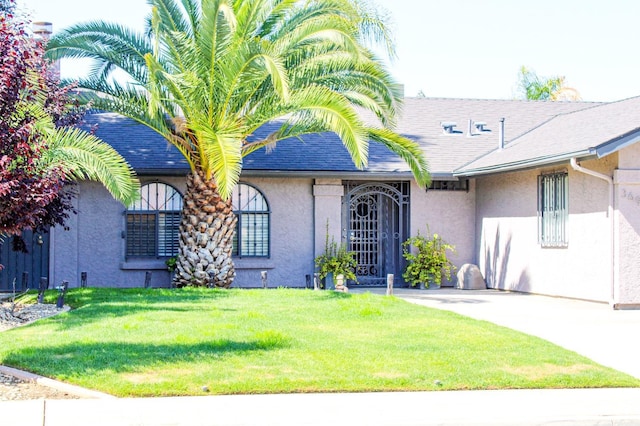 view of front of house with stucco siding and a front lawn