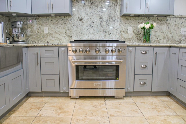 kitchen with high end range, gray cabinetry, tasteful backsplash, and light tile patterned flooring