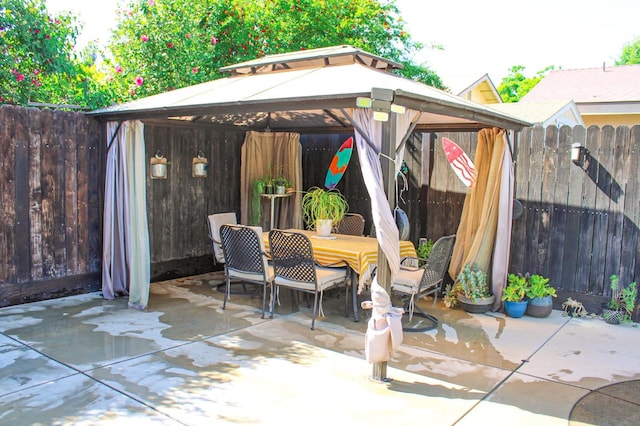 view of patio with a gazebo, outdoor dining space, and a fenced backyard
