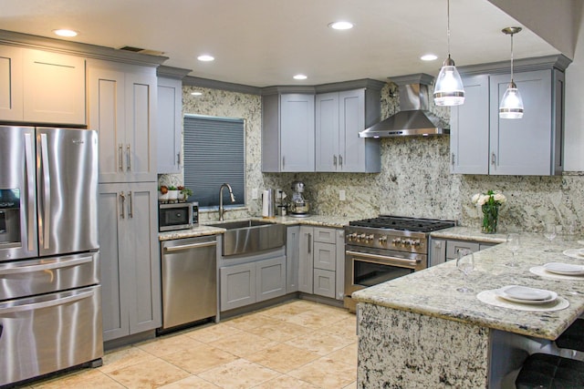 kitchen featuring stainless steel appliances, wall chimney exhaust hood, gray cabinets, a sink, and recessed lighting
