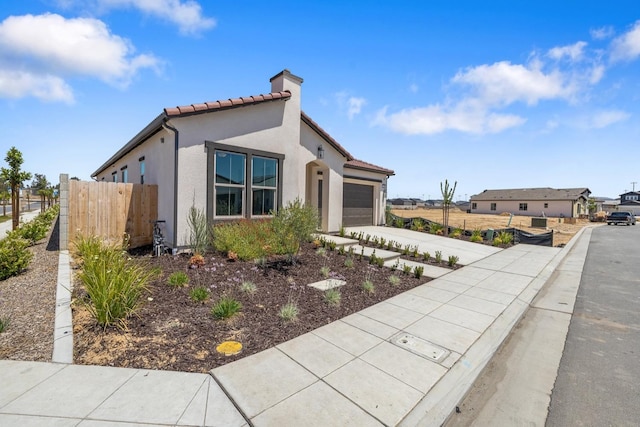 mediterranean / spanish home with a garage, fence, a chimney, concrete driveway, and a tile roof