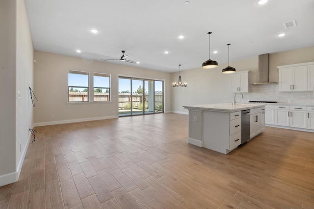 kitchen with wall chimney range hood, open floor plan, ceiling fan, recessed lighting, and dishwasher