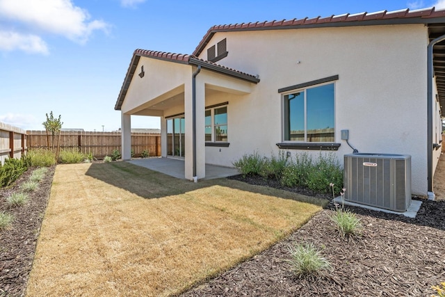 rear view of property with central AC unit, a patio area, stucco siding, and a tiled roof
