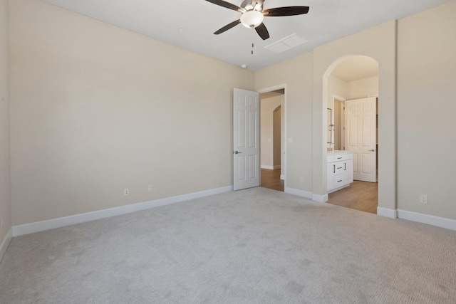 unfurnished bedroom featuring light colored carpet, baseboards, arched walkways, and a ceiling fan