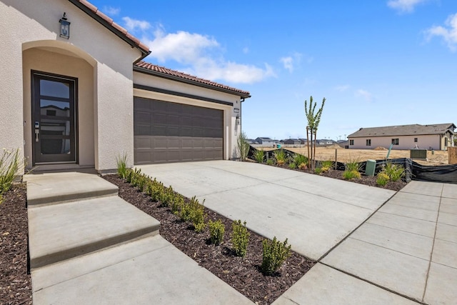 exterior space featuring concrete driveway, an attached garage, stucco siding, and a tile roof