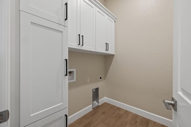 washroom featuring electric dryer hookup, baseboards, wood finished floors, cabinet space, and hookup for a washing machine