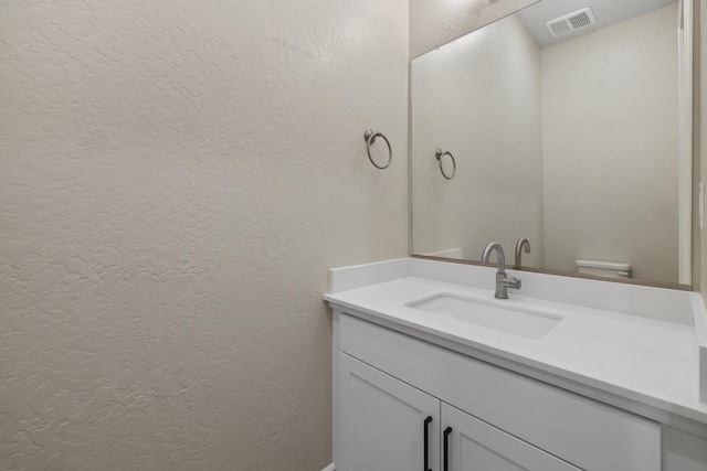 bathroom with a textured wall and vanity
