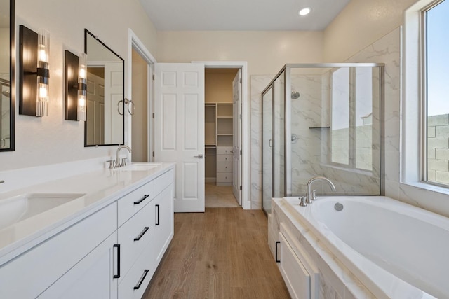 full bath with a stall shower, wood finished floors, a garden tub, a spacious closet, and double vanity