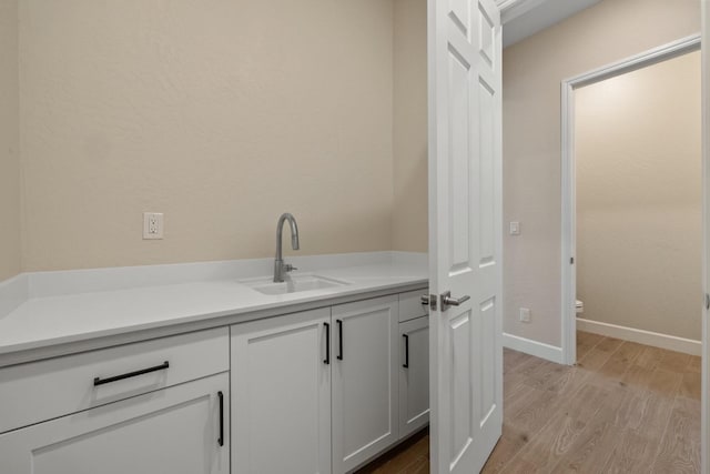 washroom with a sink, light wood-style floors, and baseboards