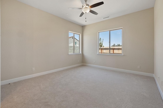 spare room with a ceiling fan, light carpet, and baseboards