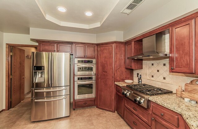 1025 E Cambridge Ave, Visalia, CA 93292 - kitchen featuring stainless steel appliances, wall chimney exhaust hood, tasteful backsplash, light tile patterned flooring, and light stone countertops