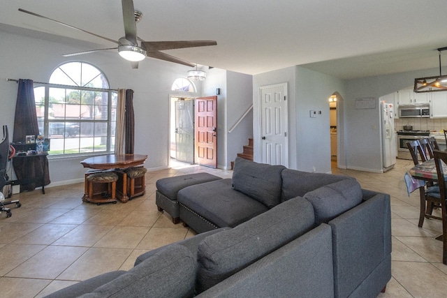 3626 E Stewart Ct, Visalia, CA 93292 - living room with light tile patterned floors, a ceiling fan, stairs, arched walkways, and baseboards