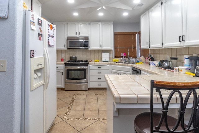3626 E Stewart Ct, Visalia, CA 93292 - kitchen with stainless steel appliances, recessed lighting, tile countertops, light tile patterned flooring, and backsplash