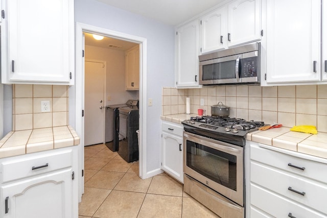3626 E Stewart Ct, Visalia, CA 93292 - kitchen with stainless steel appliances, washer and clothes dryer, tile countertops, and white cabinetry