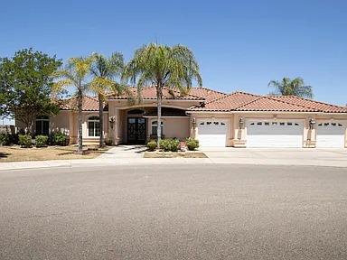 mediterranean / spanish house with a garage, stucco siding, driveway, and a tile roof