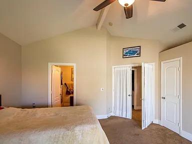 carpeted bedroom featuring beam ceiling, high vaulted ceiling, baseboards, and a ceiling fan