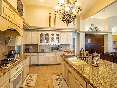 kitchen featuring white oven, stainless steel gas stovetop, a sink, backsplash, and a high ceiling