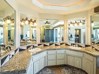 bathroom featuring a tray ceiling, crown molding, and double vanity